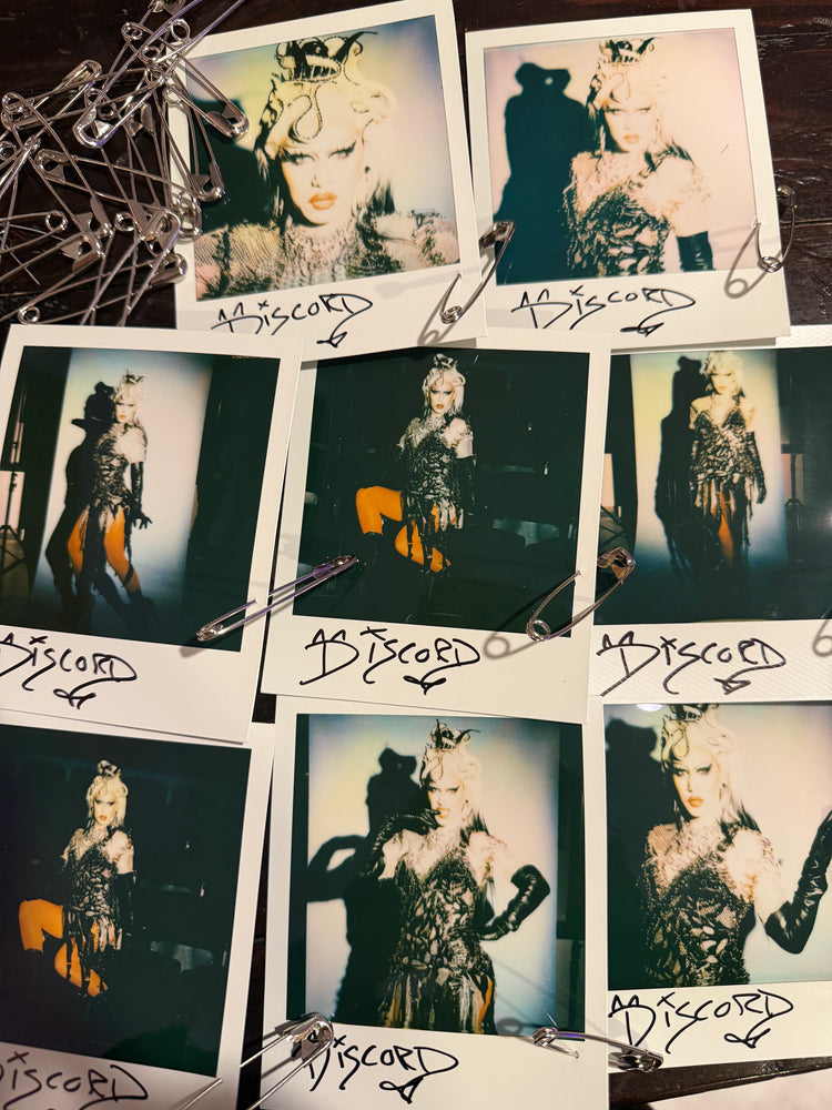 One-of-a-kind, signed full-size Polaroid featuring a safety pin from the party dress design challenge.